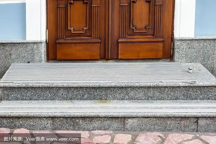 灰色花岗岩门槛,台阶上覆盖了防滑胶条,建筑正面棕色木门,正面特写.