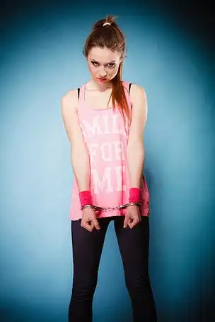 青少年犯罪,逮捕和监狱 — 戴着手铐蓝色背景的犯罪青少年女囚犯