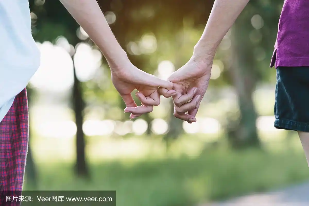 特写两个人在自然背景上勾住对方的小指.