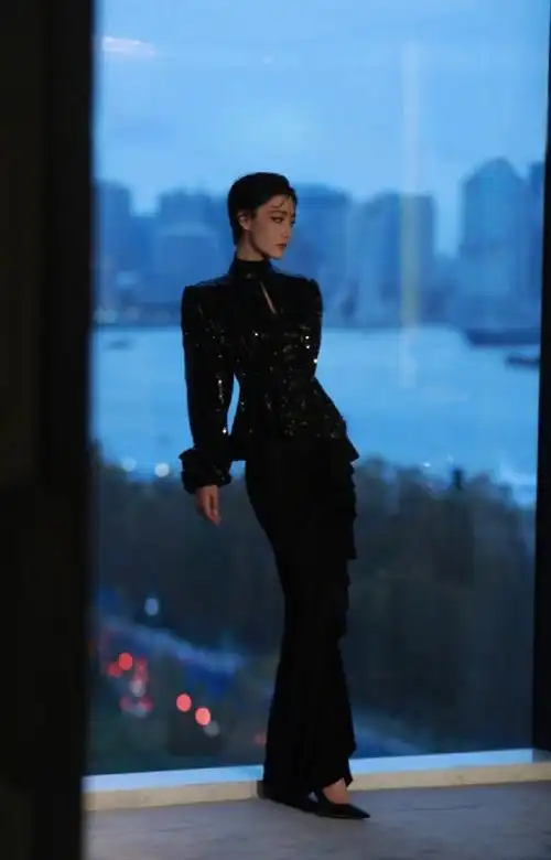 蓝色背景的落地窗前站着一个面容姣好的女子