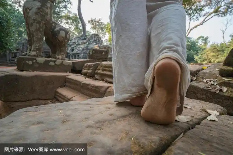 近距离观察一名女子赤脚行走在柬埔寨吴哥窟的古庙上