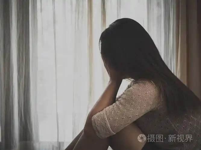 悲伤的女人抱着她的膝盖和哭时独自一人坐