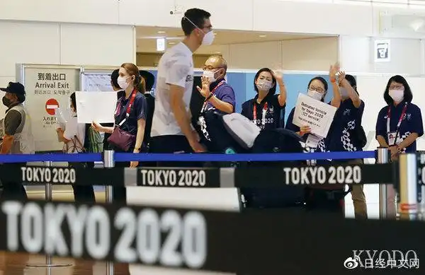 戴着口罩挥手迎接来访外国运动员的东京奥运会工作人员(7月15日,kyodo