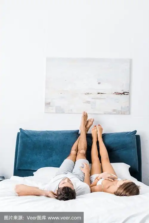 一对年轻夫妇抬着腿躺在床上