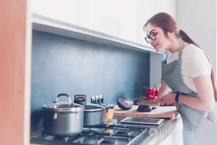 年轻女子在厨房用平板电脑做饭