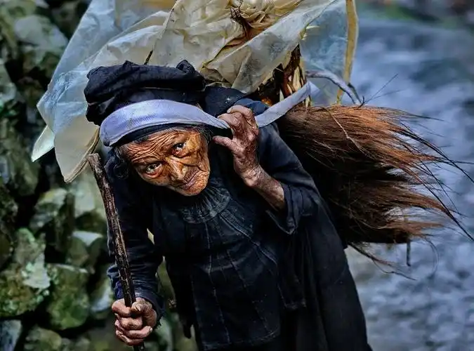 云南红河州建水县的一个偏僻的哈尼族村寨,霏霏细雨中,一位老妪肩披