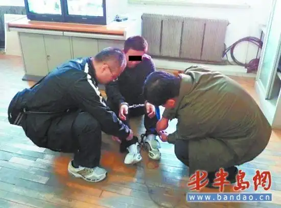 逃犯王某被戴上手铐脚镣.