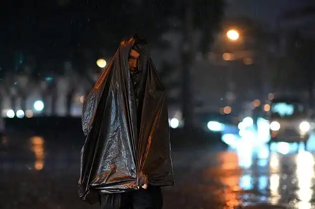 2021年8月23日,北京,雨中的夜晚,市民披着一件黑色塑料袋挡雨.