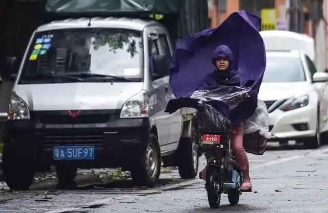 番禺区富华西路,一位骑车市民的雨衣被大风吹起.