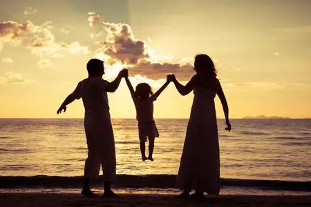 幸福的家庭的剪影在一元在沙滩上玩的人照片