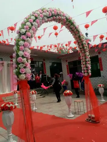 院子里是婚庆公司为婚礼仪式搭建的花拱门,铺的红地毯,还有乡邻助兴的