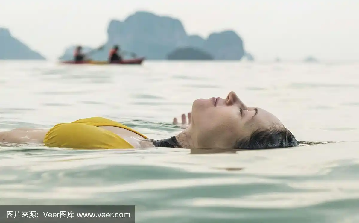 美丽的女孩躺在水里,眼睛闭着