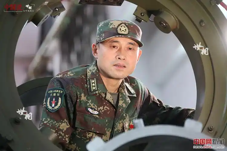 "在5米高台上,一名个子不高,身材瘦小的上校军官,一边抬着铁架门