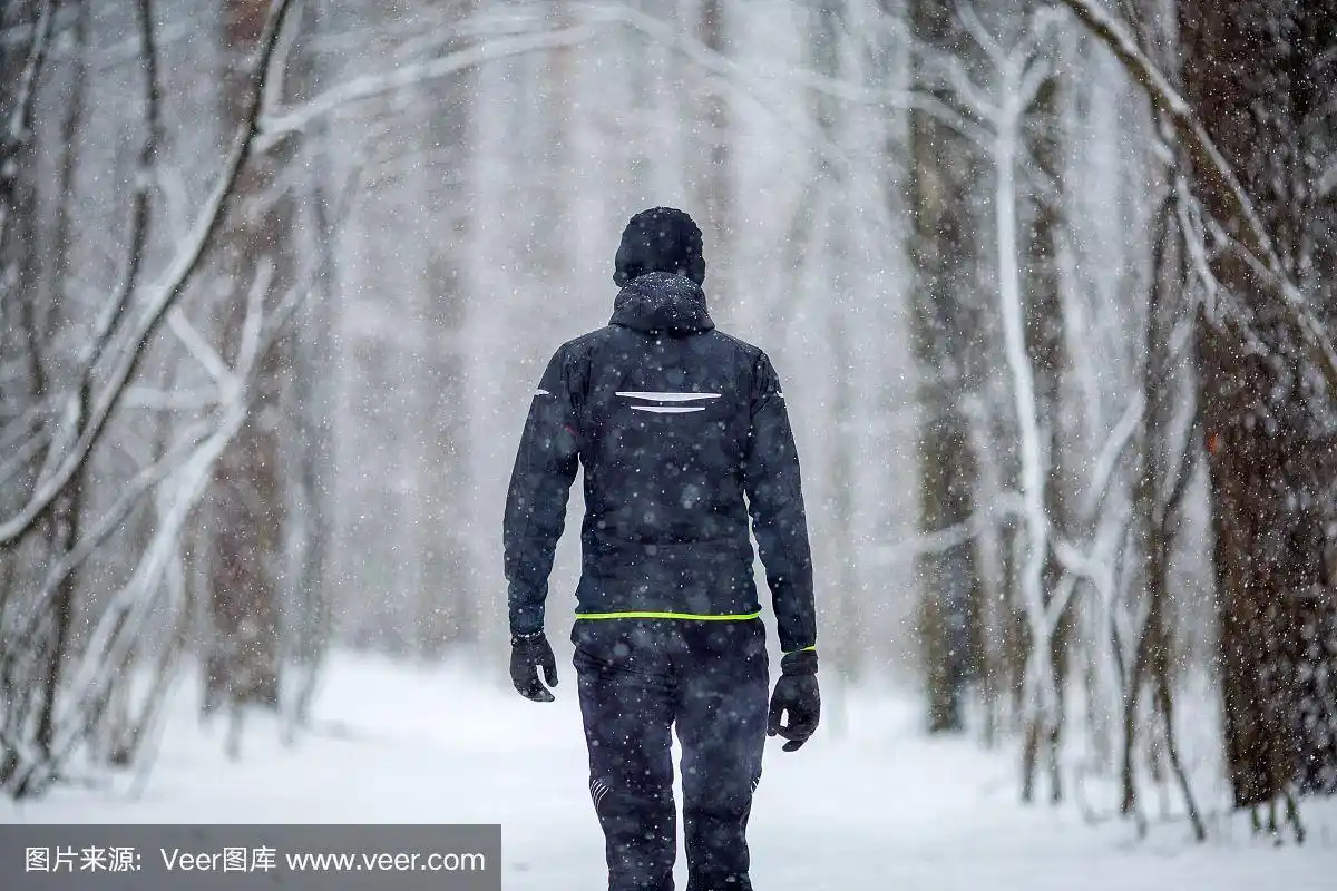 这张照片摄于一个穿着运动服的男人在冬天跑步的背影