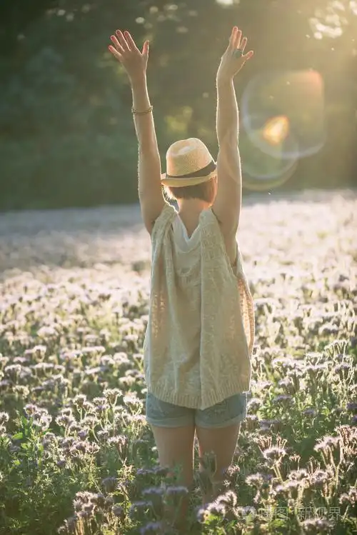 美丽的女人用享受和平,宁静自然的伸开双臂拥抱金色阳光落日的余晖