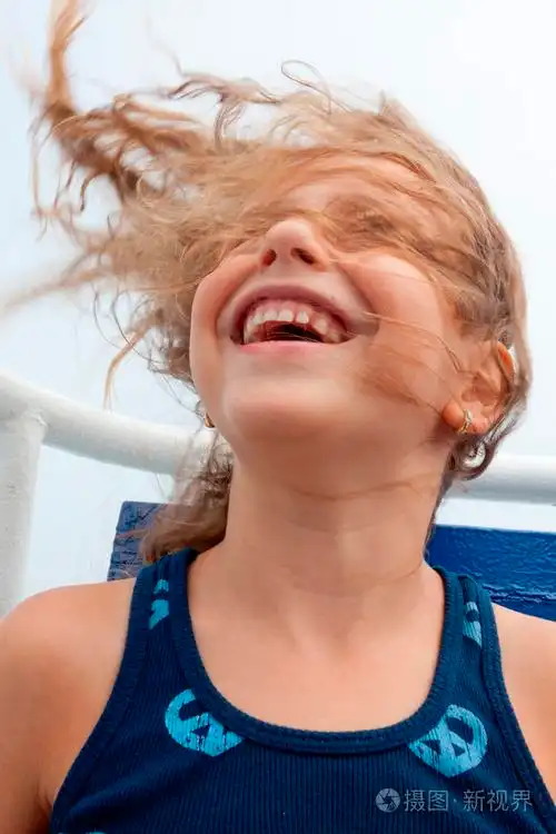 可爱的小女孩她的头发吹在风中笑