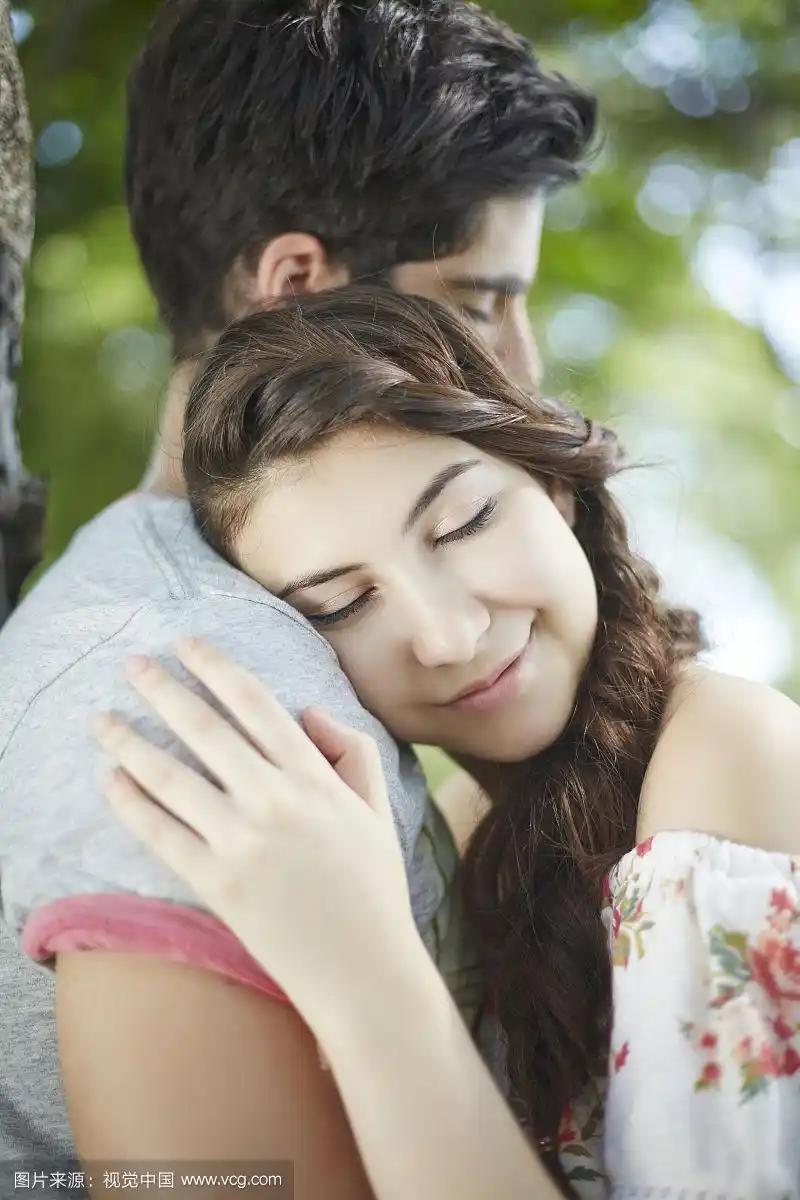 穿着休闲装的情侣在公园里拥抱的照片