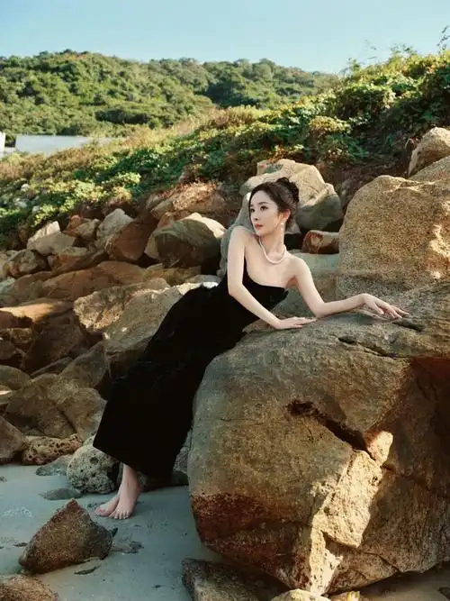 阳光沙滩,海边裸石,赤足的杨幂身穿纯黑色抹胸礼服,脖子上带着珍珠