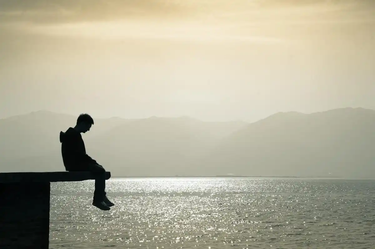 一个人,面朝苍山洱海沉思着,像是一个孤独患者