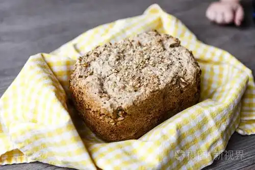 在木制的桌子上的黄色布自制的麦片面包