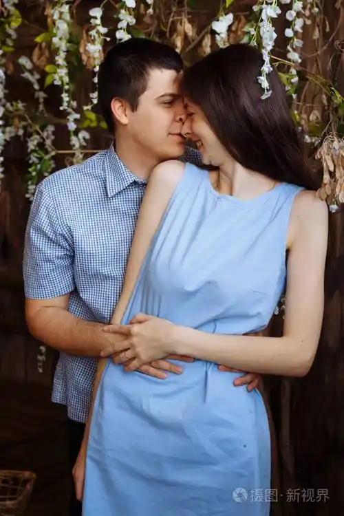 男人拥抱一个女孩微笑着一对相爱的情侣蓝色的裙子和衬衫日期情人节