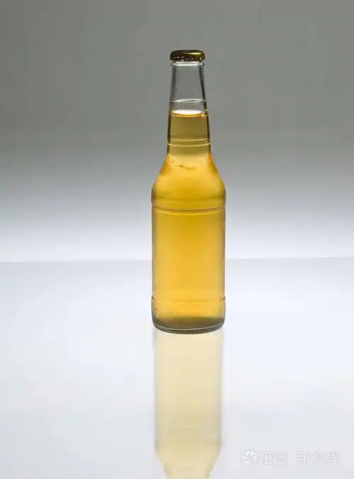 金色的淡啤酒在一个清澈的瓶子后面反射地点燃