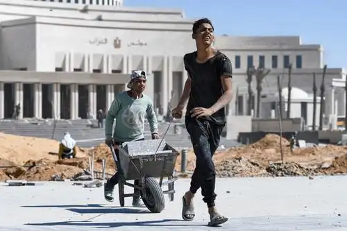 工人们在埃及新议会大厦建筑工地前运送手推车