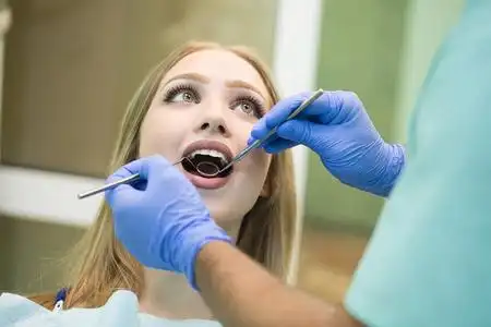 照片特写照片,年轻女子坐在牙医的椅子上,张开嘴在牙医办公室检查照片