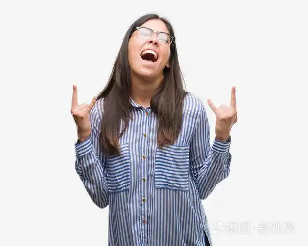 年轻漂亮的西班牙裔商业妇女大声喊着疯狂的表情做摇滚符号用手.