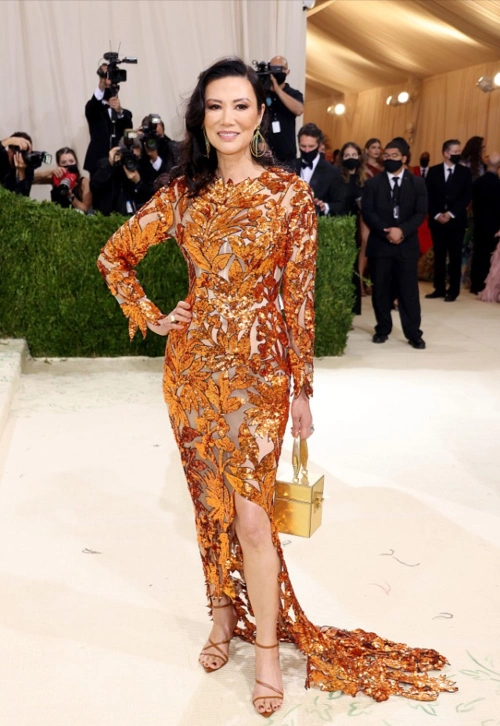 54岁的邓文迪化紫色眼妆媚而不妖,穿橘色花纹裙,衬得很高贵