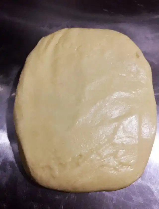 将包好的油酥面团翻面,擀成椭圆形,自上而下卷起,静置松懈15分钟左右