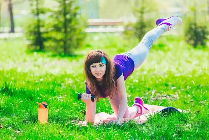 在公园的健身女孩和从事各种练习哑铃与垫.布鲁内特参加户外体育活动