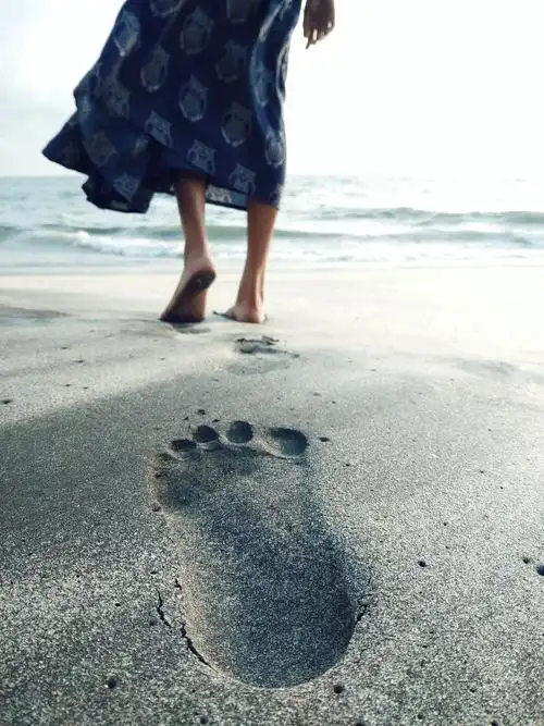 一名女子赤脚在海边行走的照片