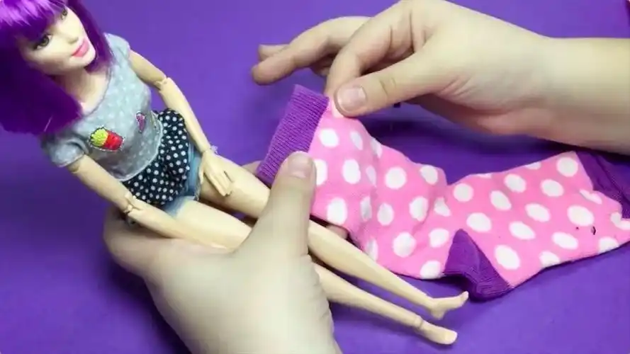 1,取出一只袜子并将其翻到反面,用袜头包住芭比娃娃的脚.