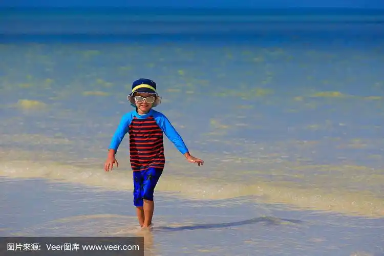 小男孩在夏天的海滩上玩水