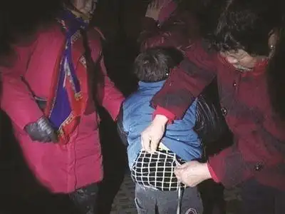 孩子腰部被拴着绳子捆在石凳上,市民为他解绳子.