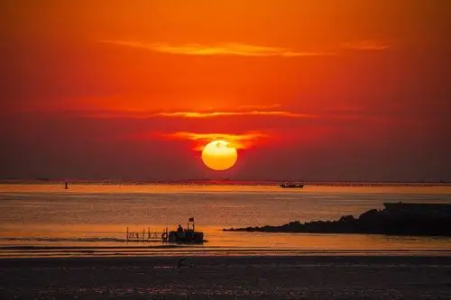 海面泛起金光;天边有霾天上有较薄的云时則火红火红的太阳从海上徐徐