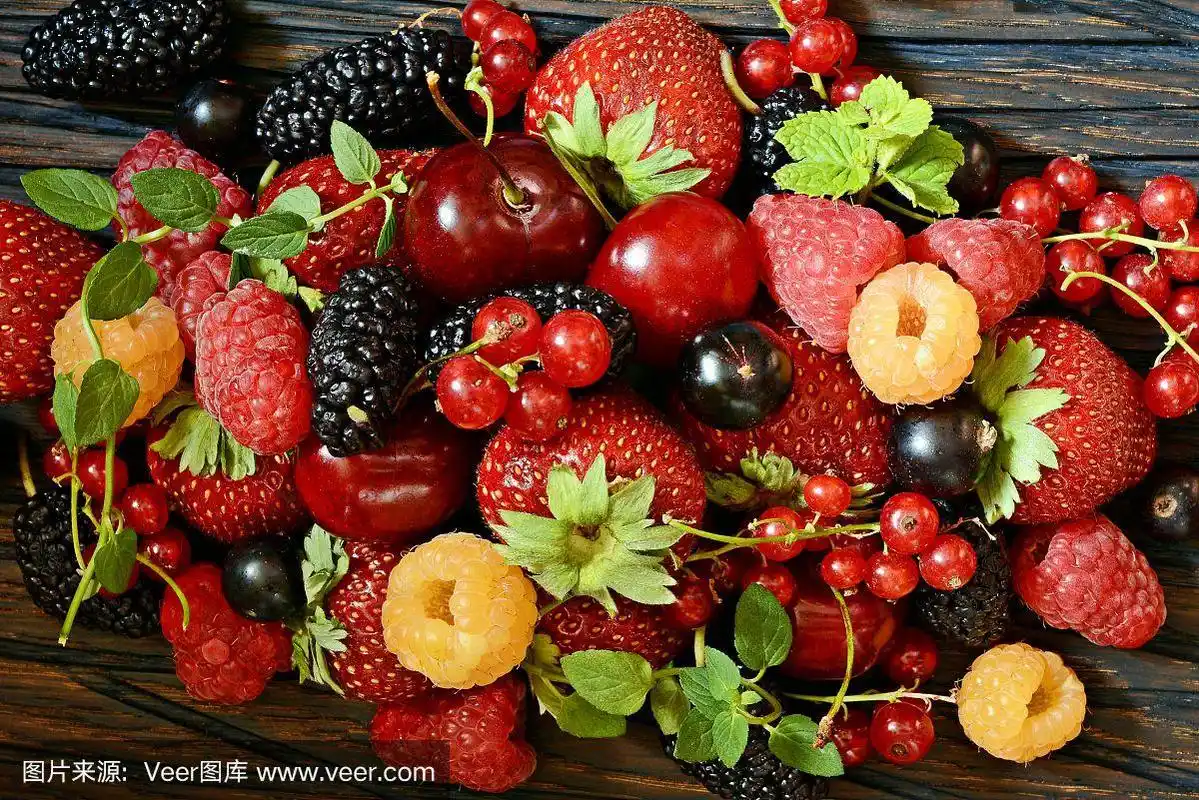 浆果类水果,如草莓,蓝莓,红加仑子,覆盆子和黑莓放在木板上.