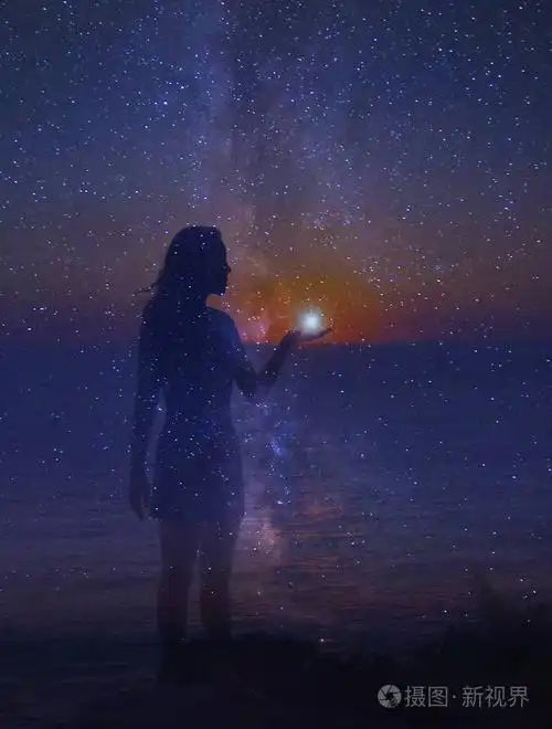 夜空中满是星星, 一只手上有颗星星的站立女孩的剪影.