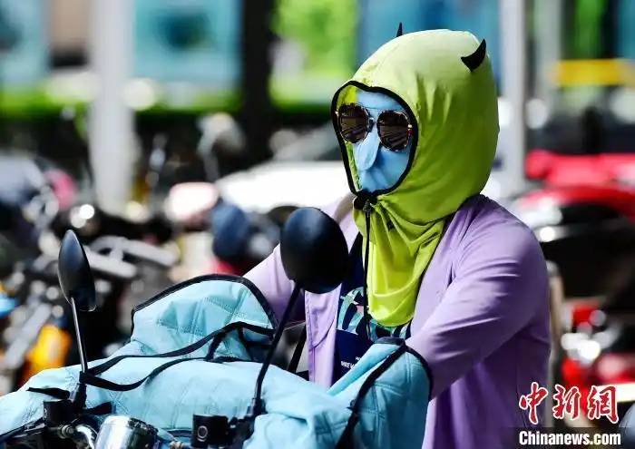 资料图:6月17日,福建福州市民烈日下"全副捂装"出行. 张斌 摄