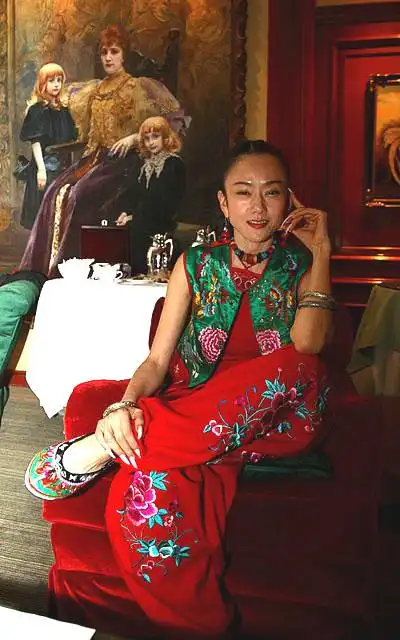 杨丽萍身着民族服装,绣花布鞋,在所住旅馆大堂的大幅法国贵族肖像画前