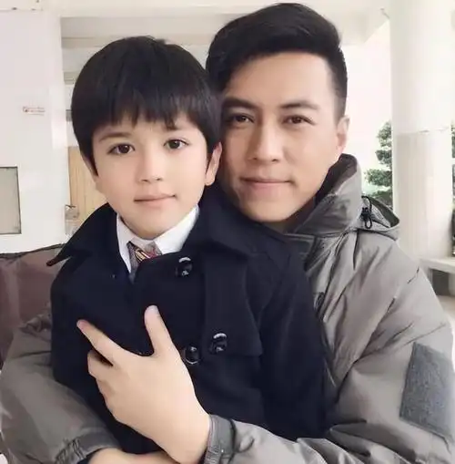 靳东抱着小儿子给大儿子看,表情十分温柔.