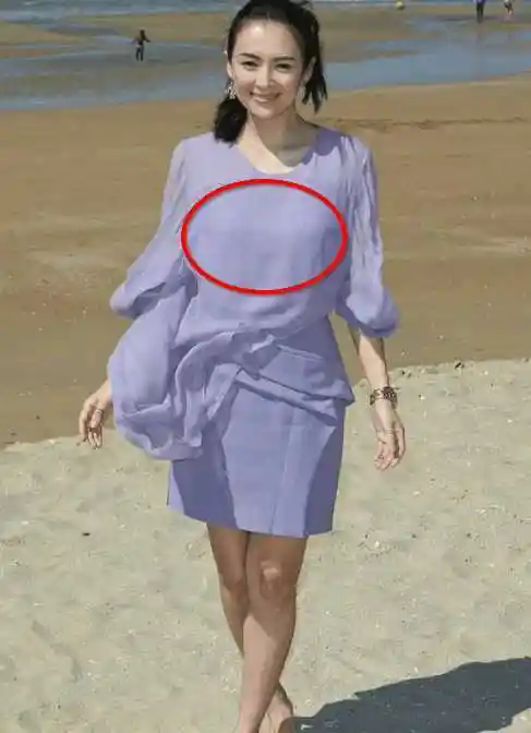 章子怡身穿紫色飘逸短裙海滩游玩,海风吹起却