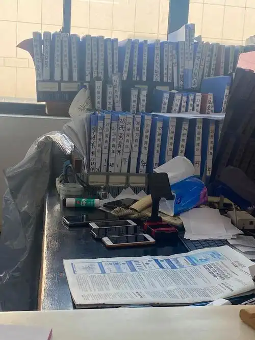 李继延的办公桌上摆着6部手机和许多收录会员资料的文件夹.