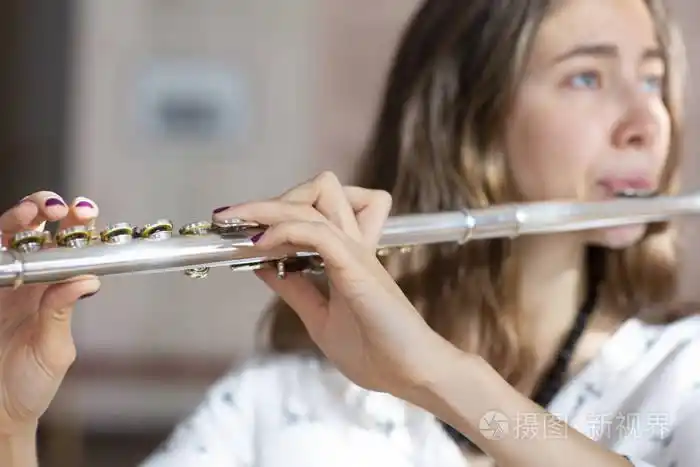 音乐会期间,一位美丽的女士在女孩手中演奏长笛时摆姿势.