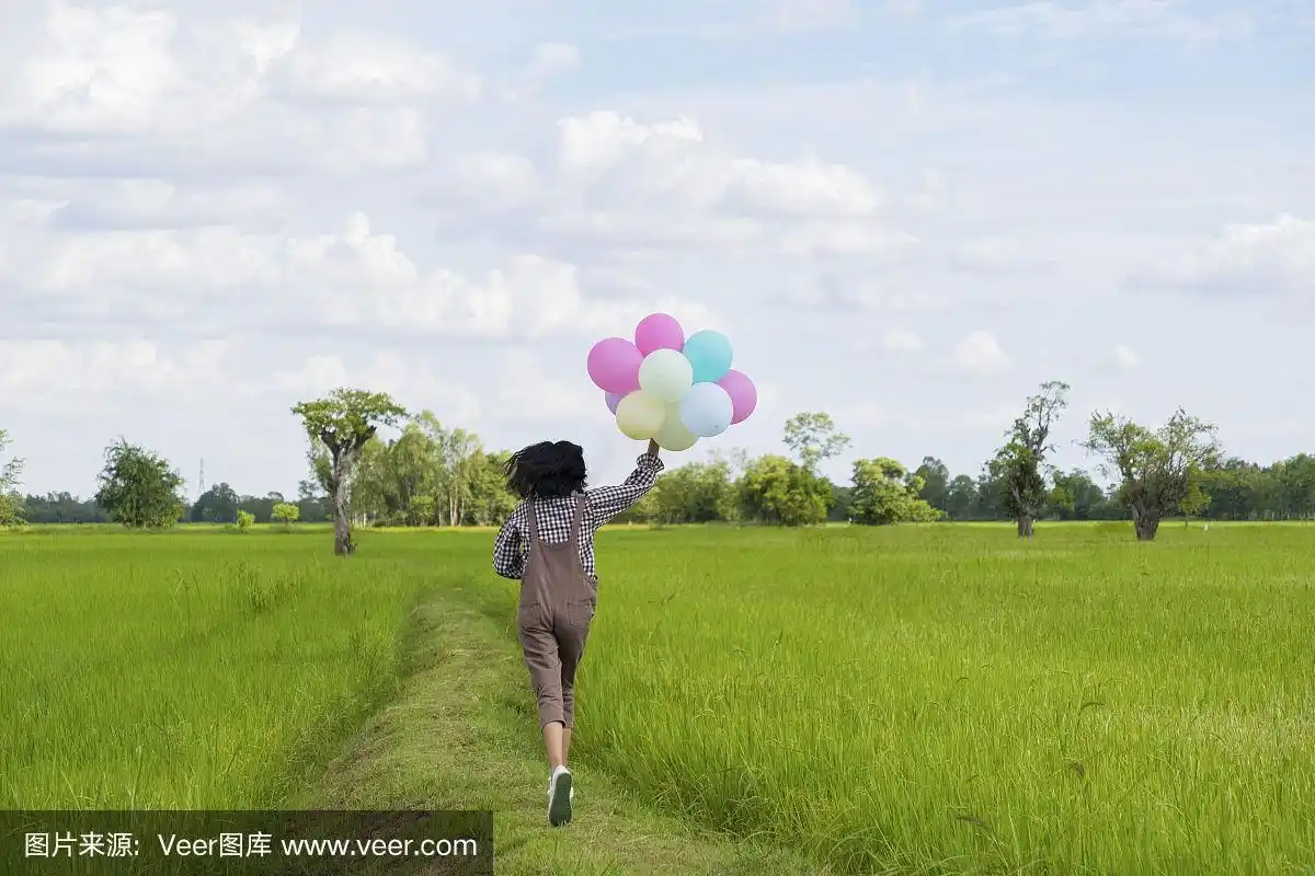 快乐的亚洲小女孩拿着气球在美丽的稻田里奔跑,大自然的背景.