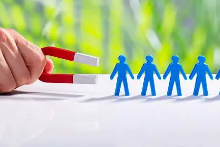 磁铁举行商人的手吸引蓝人的身影站在一排马蹄磁铁照片