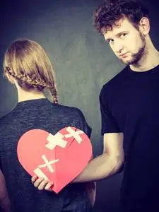 悲伤感情破裂的夫妻女人和男人捧红纸心固定与石膏绷带.