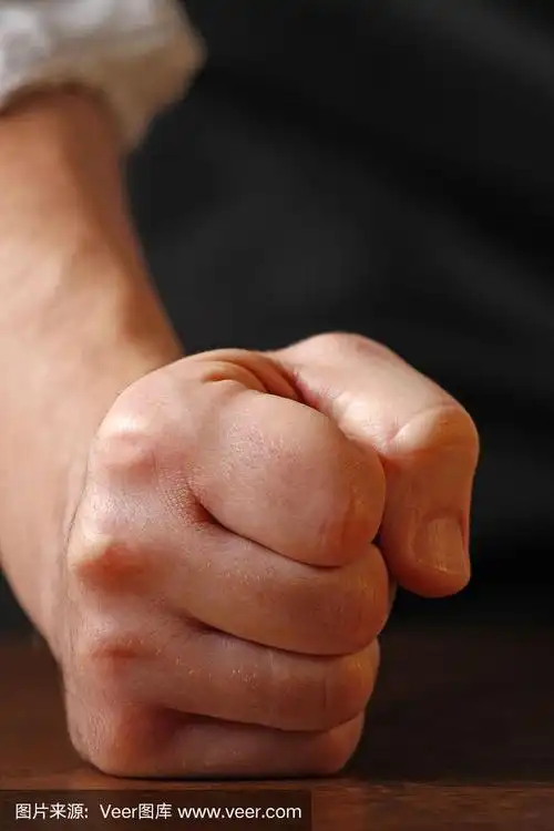 一个男人紧握着拳头敲打着桌子.