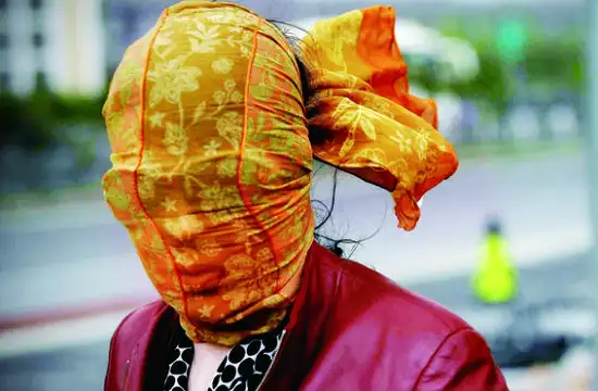 前天中午1时许,在四惠公交车站,一位女士用纱巾将自己的头部包起来